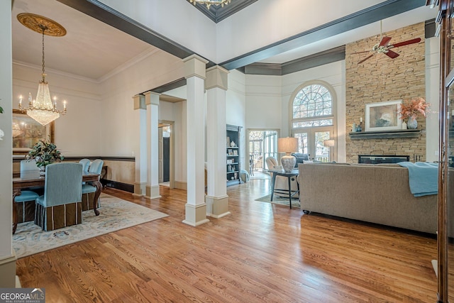 dining space with a high ceiling, a fireplace, wood finished floors, ornate columns, and crown molding