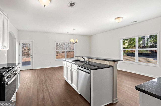 kitchen with sink, appliances with stainless steel finishes, white cabinets, pendant lighting, and dark wood-type flooring