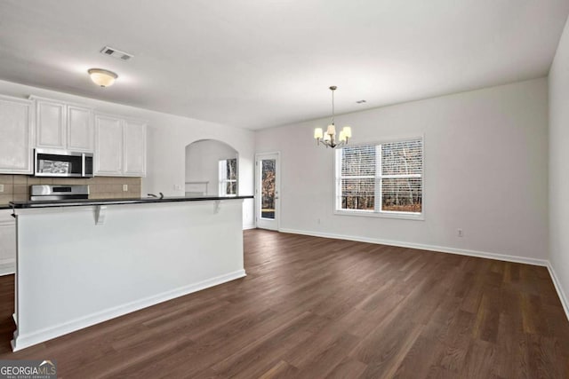 kitchen featuring stainless steel appliances, a notable chandelier, pendant lighting, decorative backsplash, and white cabinetry