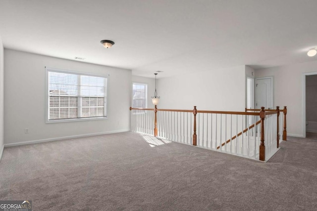 unfurnished room featuring a chandelier and carpet