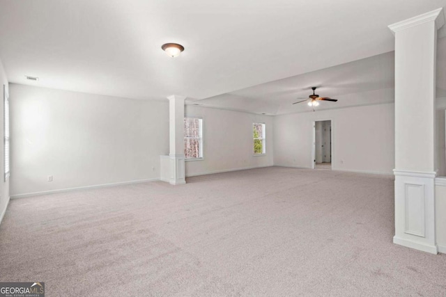 carpeted empty room with decorative columns and ceiling fan