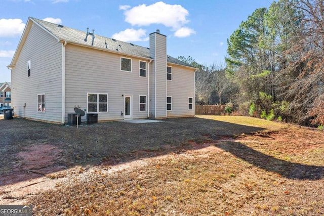 rear view of house with central AC unit, a patio, and a lawn