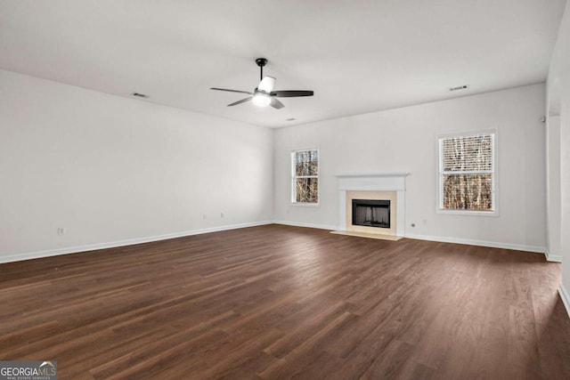 unfurnished living room featuring dark wood-type flooring, ceiling fan, and a healthy amount of sunlight