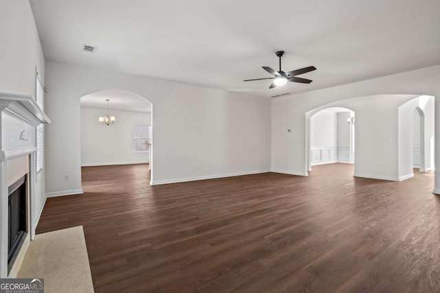 unfurnished living room featuring ceiling fan with notable chandelier and dark wood-type flooring