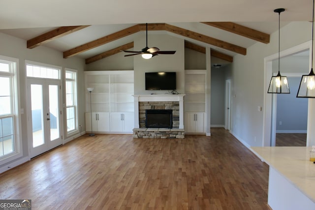 unfurnished living room featuring ceiling fan, built in features, a wealth of natural light, and a fireplace