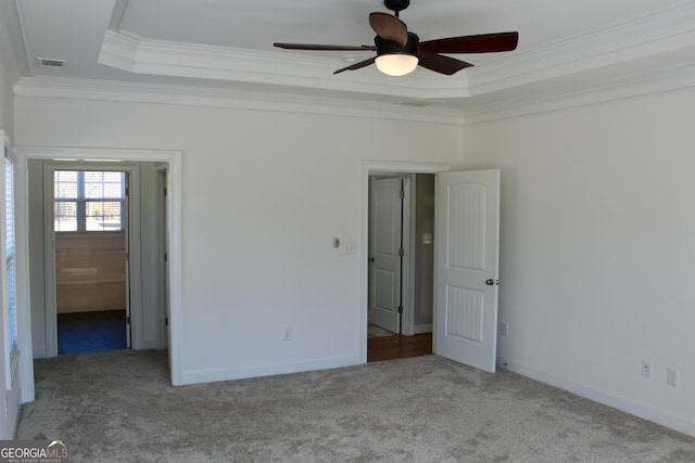 interior space featuring ceiling fan, a tray ceiling, crown molding, and light colored carpet