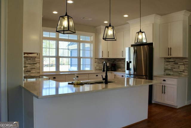 kitchen with tasteful backsplash, stainless steel fridge, white cabinetry, and pendant lighting