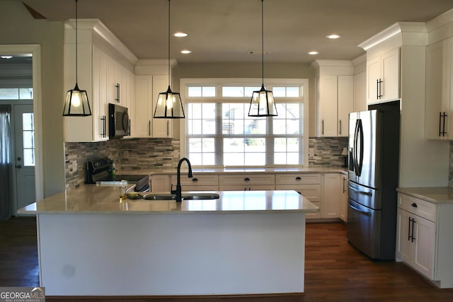 kitchen featuring sink, stainless steel appliances, white cabinets, and decorative light fixtures