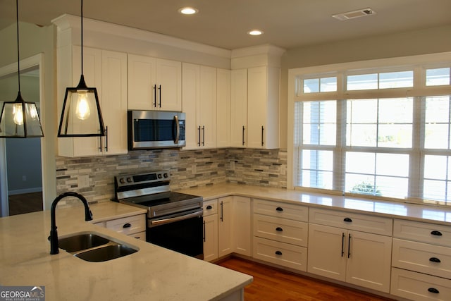 kitchen featuring stainless steel appliances, white cabinets, sink, and hanging light fixtures