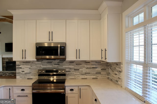 kitchen with white cabinets, appliances with stainless steel finishes, light stone countertops, and tasteful backsplash