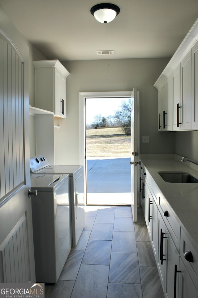 washroom featuring sink, cabinets, and washing machine and clothes dryer