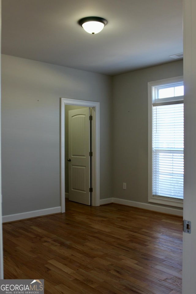 spare room featuring a wealth of natural light and dark hardwood / wood-style floors