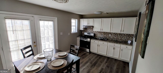 kitchen with backsplash, stainless steel stove, dark hardwood / wood-style flooring, white cabinetry, and dark stone counters