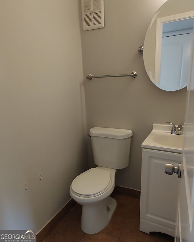 bathroom with toilet, vanity, and tile patterned flooring