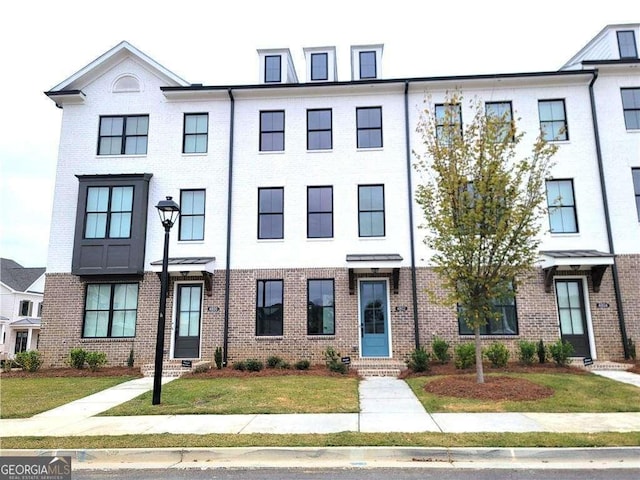 townhome / multi-family property featuring a front lawn