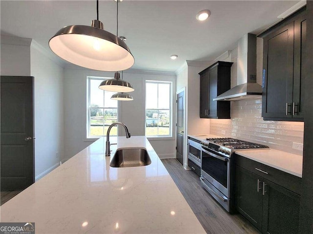 kitchen featuring backsplash, gas range, light stone countertops, wall chimney exhaust hood, and sink