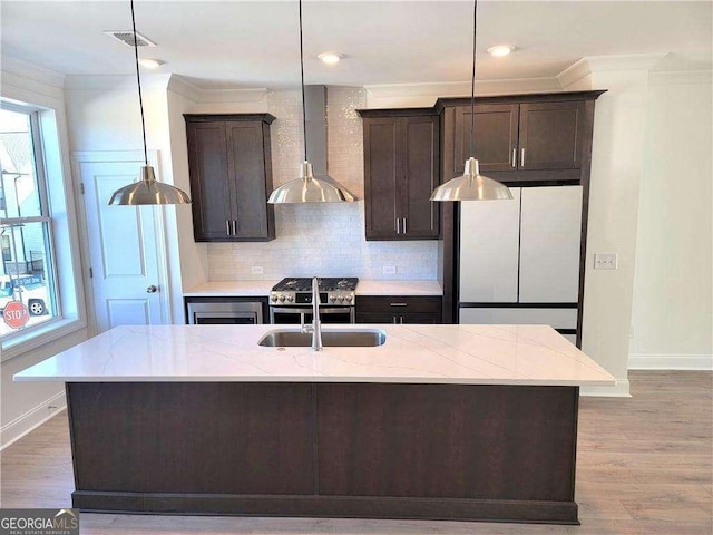 kitchen featuring white fridge, wall chimney exhaust hood, hardwood / wood-style flooring, and a kitchen island with sink