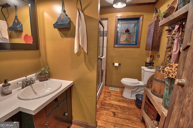 bathroom with toilet, wood-type flooring, vanity, and walk in shower