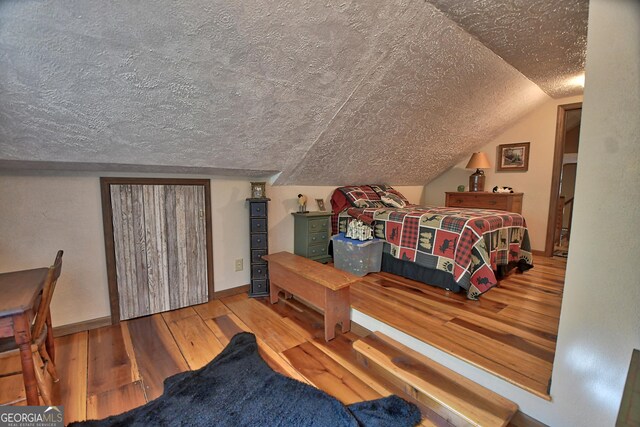 bedroom featuring lofted ceiling, a textured ceiling, and hardwood / wood-style flooring