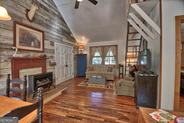 living room with high vaulted ceiling, wood walls, ceiling fan, and dark hardwood / wood-style flooring