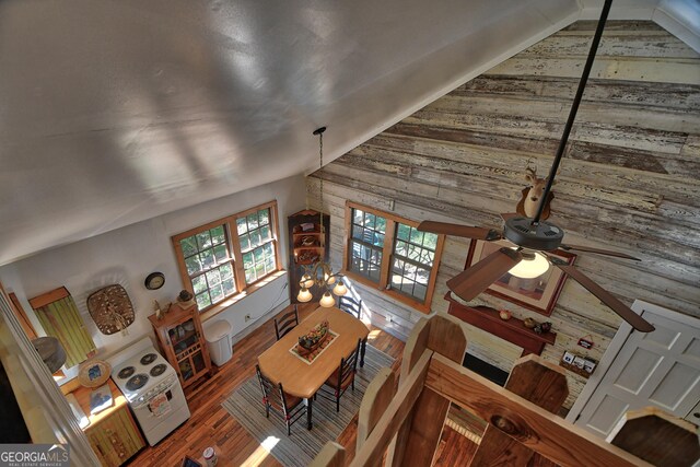 living room with ceiling fan, wooden walls, lofted ceiling, and wood-type flooring