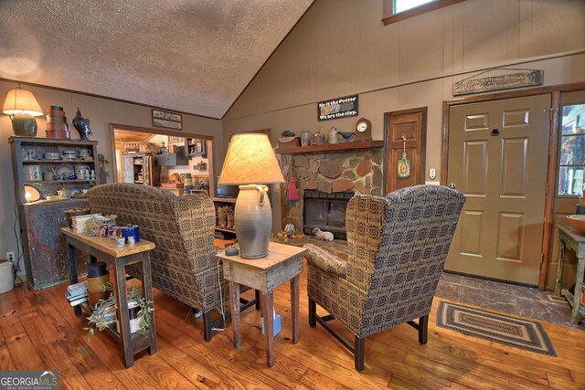 living room featuring hardwood / wood-style flooring, a textured ceiling, vaulted ceiling, and ornamental molding