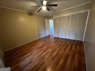 unfurnished bedroom with dark hardwood / wood-style flooring, a closet, and ceiling fan