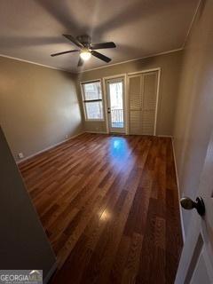 spare room featuring ornamental molding, dark wood-type flooring, and ceiling fan