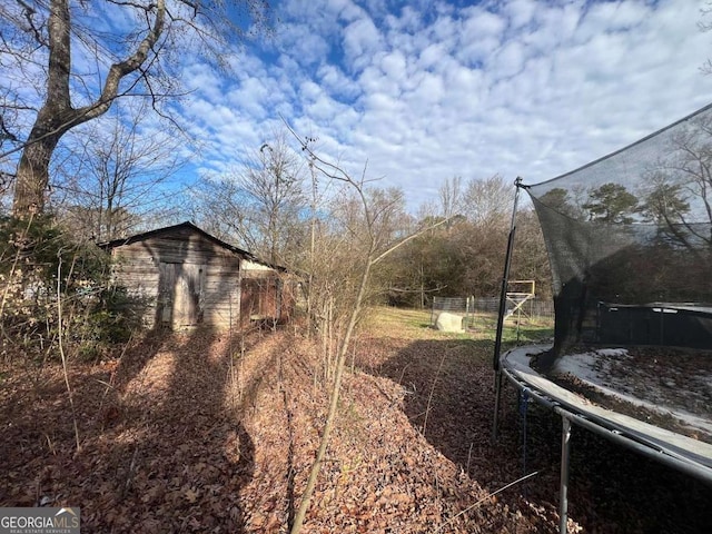 view of yard with a trampoline and a storage unit