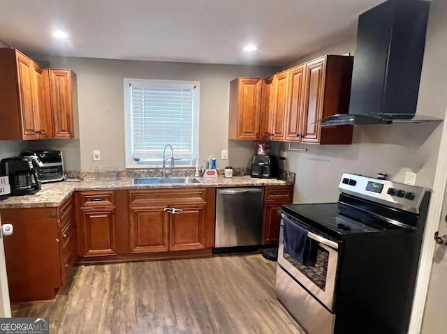 kitchen with light stone countertops, wall chimney range hood, stainless steel appliances, sink, and light hardwood / wood-style flooring