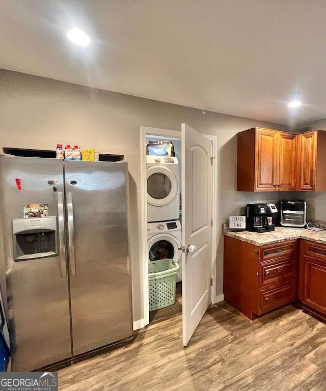 kitchen with stainless steel fridge, stacked washing maching and dryer, and light wood-type flooring