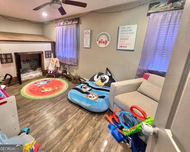 game room featuring ceiling fan, hardwood / wood-style flooring, and wooden walls