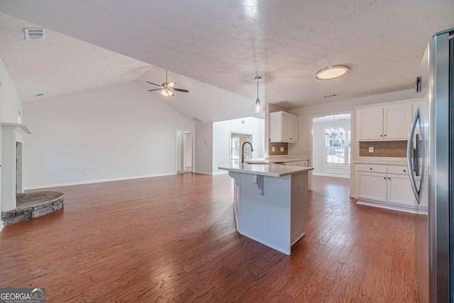 kitchen with white cabinets, decorative backsplash, a kitchen breakfast bar, sink, and stainless steel fridge