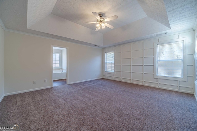 carpeted empty room featuring a textured ceiling, ceiling fan, and a tray ceiling