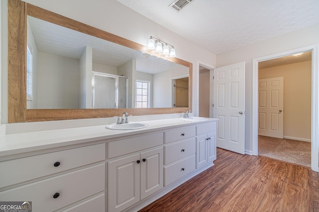 bathroom featuring a textured ceiling, a shower with shower door, hardwood / wood-style floors, and vanity