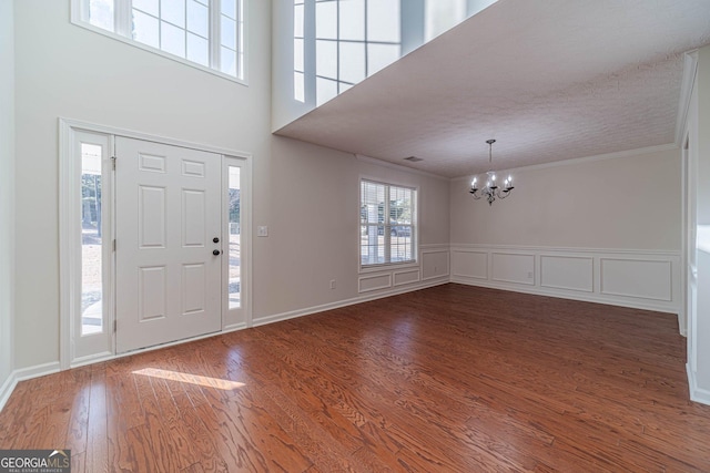 entrance foyer featuring an inviting chandelier, ornamental molding, and hardwood / wood-style floors