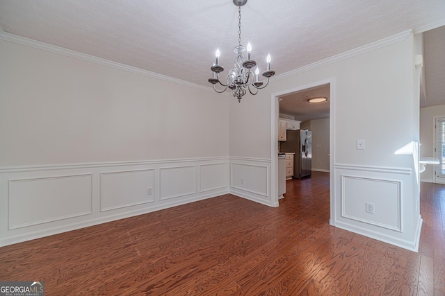 spare room featuring crown molding, dark wood-type flooring, an inviting chandelier, and a textured ceiling