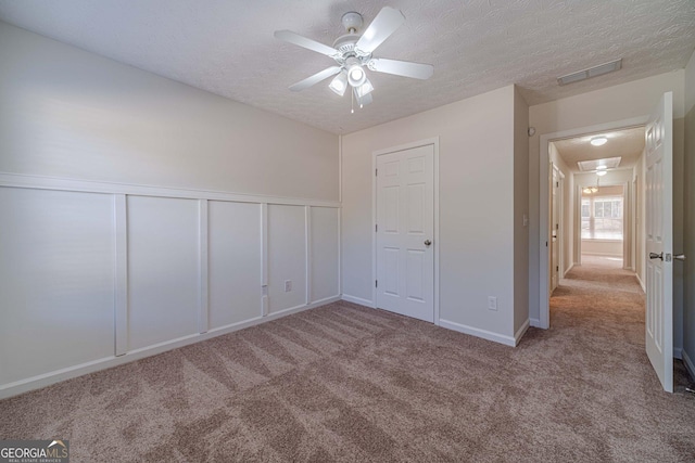 unfurnished bedroom featuring ceiling fan, a textured ceiling, and light carpet