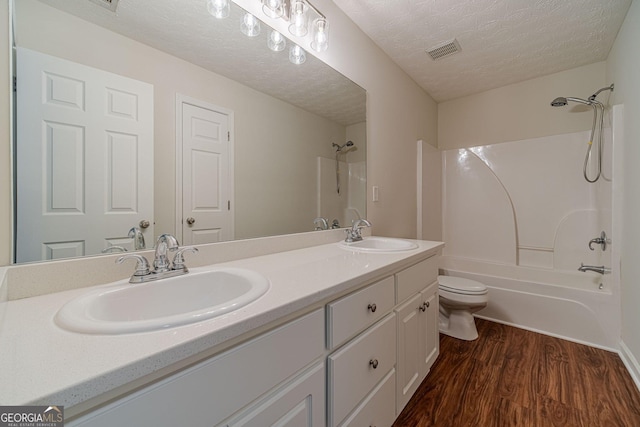 full bathroom with toilet, vanity, hardwood / wood-style flooring, a textured ceiling, and bathing tub / shower combination