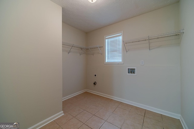 washroom featuring washer hookup, light tile patterned flooring, a textured ceiling, and hookup for an electric dryer