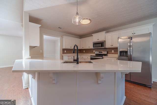 kitchen featuring white cabinetry, hardwood / wood-style flooring, stainless steel appliances, decorative backsplash, and sink