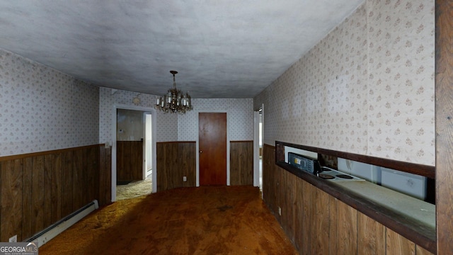 hall featuring a chandelier, carpet floors, wooden walls, and a baseboard radiator