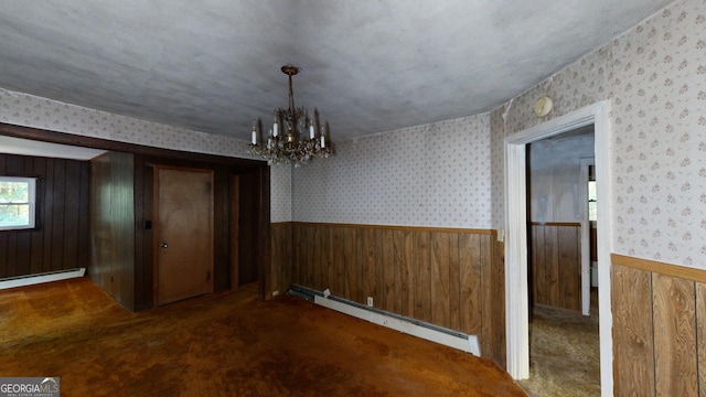 unfurnished dining area featuring carpet floors, a baseboard heating unit, and a chandelier