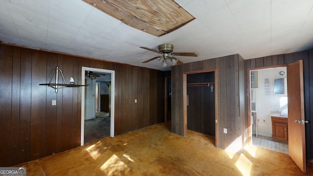 unfurnished bedroom featuring ceiling fan, light colored carpet, and ensuite bath