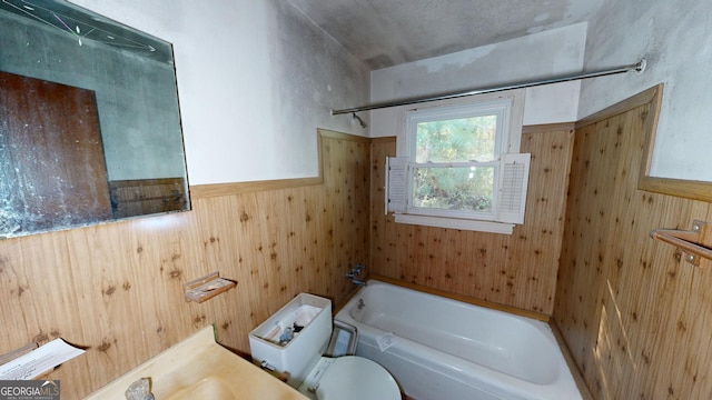 bathroom featuring toilet, bathing tub / shower combination, and wooden walls