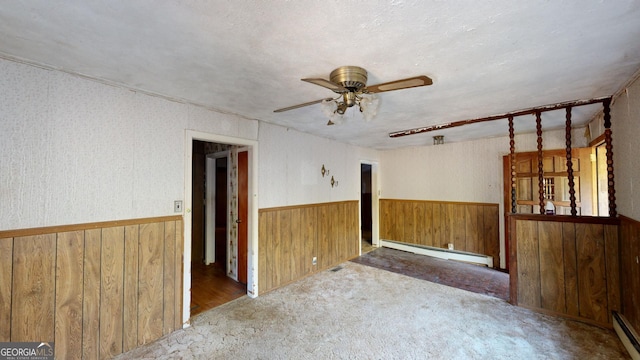 carpeted empty room with ceiling fan, a baseboard heating unit, and a textured ceiling