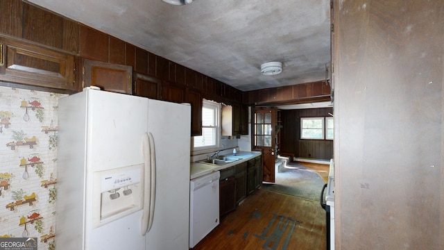 kitchen featuring brick wall, dark wood-type flooring, a wealth of natural light, and white appliances