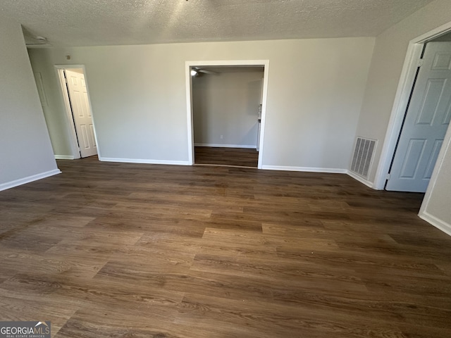 spare room featuring dark hardwood / wood-style flooring and a textured ceiling