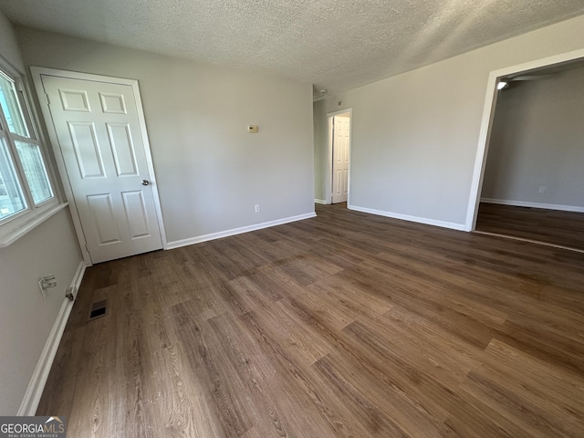 unfurnished room featuring a textured ceiling and dark hardwood / wood-style floors