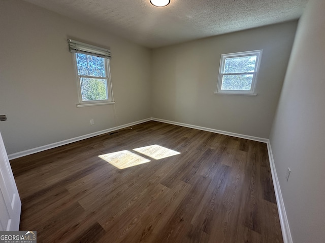 unfurnished room featuring dark wood-type flooring and a textured ceiling